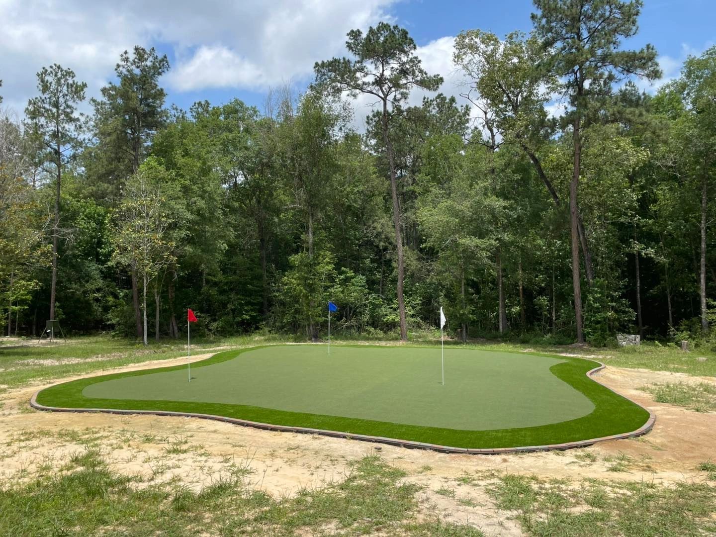 Freestanding putting green surrounded by pine trees