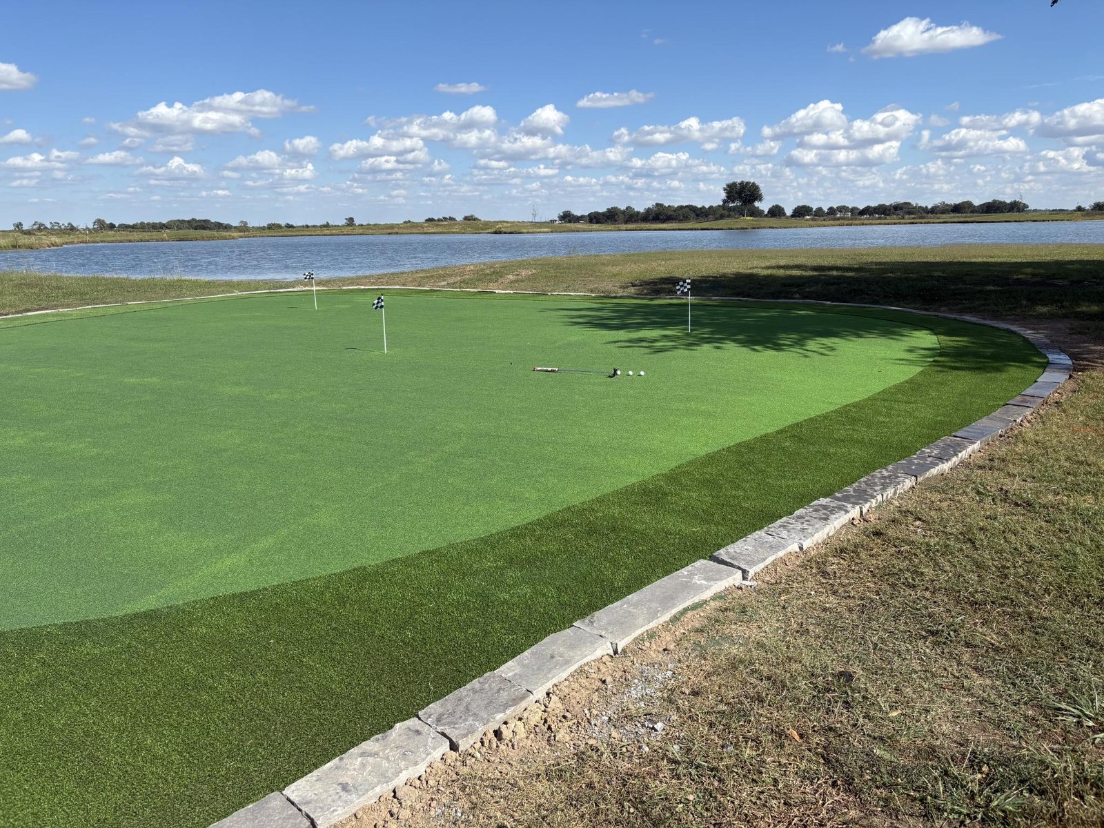 Lakeside putting green with stone border overlooking open water